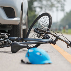 Bicycle and helmet on road next to car after accident - Robichaux Law Firm, LLC